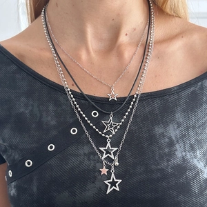 Layered silver star pendant necklace with sparkling rhinestones on textured fabric background