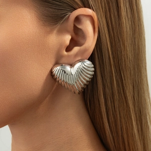 Close-up of silver-plated oversized heart earring with unique pleated metallic texture