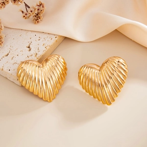 Macro detail of gold-plated heart earrings featuring a vintage textured ribbed metal surface