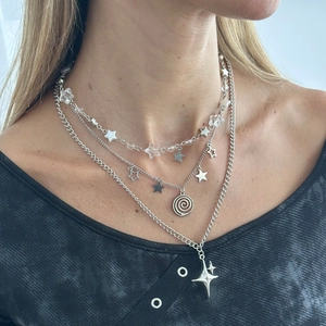 Close-up of multilayered silver necklaces with star charms and faux pearls on a model