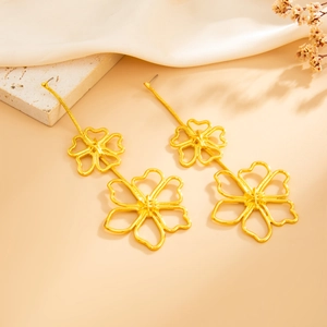Close-up of golden hollow flower drop earrings with elegant polished metal petals