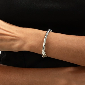 Detail of silver irregular lava texture bracelet on wrist with organic metallic design