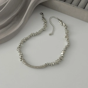 Detailed view of silver irregular metal beads necklace with a smooth curved tube pendant