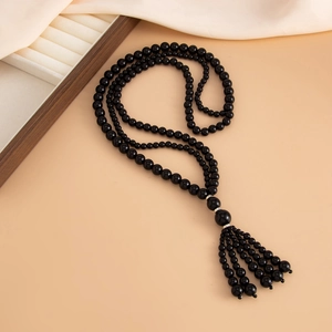 Detailed view of long black acrylic bead necklace with tassel and silver metal spacers