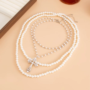Collier multi-rangs avec perles d'imitation et pendentif croix sur fond minimaliste