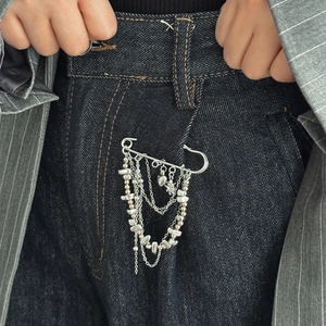 Detail of silver safety pin brooch with multi-layer chains and heart charms on denim
