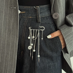 Silver safety pin accessory with pearls and star charms on denim jeans for street style