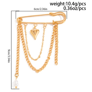 Detail of gold chain brooch with heart charms and white pearl on safety pin