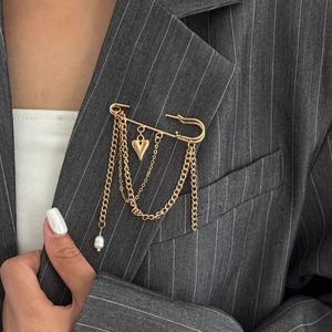 Detail of gold brooch pin with heart pendant and tassels on a grey pinstripe blazer