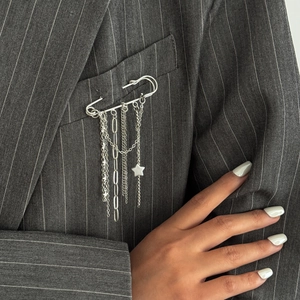 Silver safety pin brooch with hanging chains and a star charm on a grey striped suit