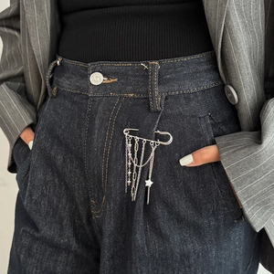 Close-up of a silver safety pin brooch with multi-layer tassel chains and star charms