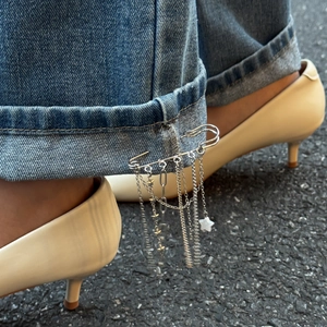 Close-up of silver star tassel pin with chains used as a denim cuff accessory