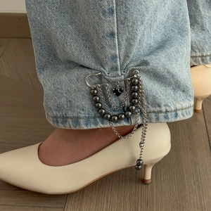 Detail of silver safety pin brooch with black heart pendant and tassels on denim