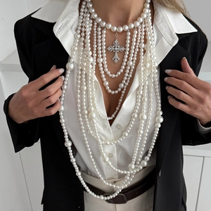 Detail van meerlaagse parelketting met grote met strass steentjes ingelegde kruis