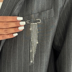 Silver safety pin brooch with layered chain tassels and star charms on a grey suit