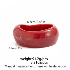 Detailed macro view of wide resin bangle with white marble texture on dark red surface