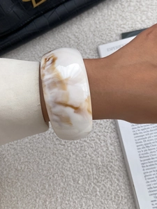 Close-up of marbled resin wide bangle with white and brown texture on model's wrist