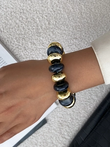 Detail of chunky gold links paired with deep blue marble resin on a model's wrist