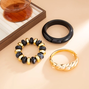 Detail of retro resin bangle, gold twisted bracelet, and marble bead bracelet set