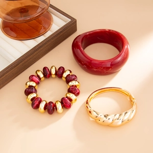 Detail of vintage gold-tone twisted bangle with deep red resin cuff and beaded bracelet