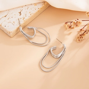 Detail of silver layered U-shaped earrings with fine snake chain tassels on stone background
