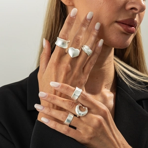 Set of matte silver minimalist rings featuring heart shapes and textured bands on a model