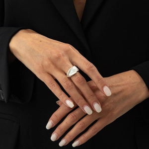 Close-up of abstract wavy silver ring with sculpted leaf texture worn on finger