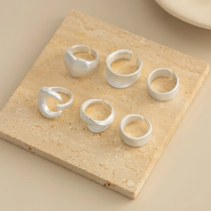Close-up of a 6-piece matte silver ring set with heart and textured bands on stone
