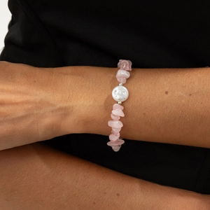 Close-up of pink quartz beaded bracelet with a baroque pearl pendant on woman's wrist