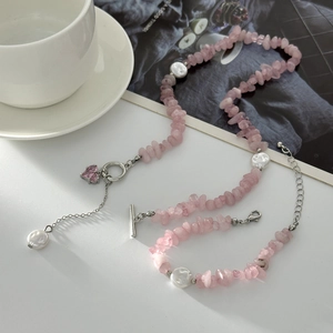 Pink crystal gravel and pearl necklace set with silver heart pendant on white background