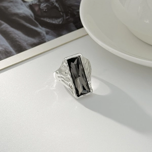 Detailed close-up of a silver ring with rectangular black gemstone and hammered texture
