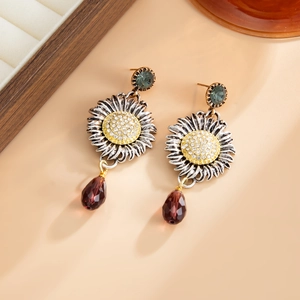 Dettaglio di orecchini a girasole vintage con borchie a smeraldo e perle bordeaux