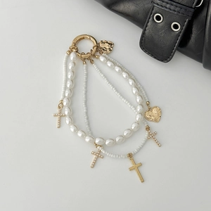 Elegant multi-layer pearl bag charm with gold crosses and heart charms on white background