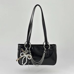 Detail of black patent leather Y2K bag with leopard bow and silver chain accessories