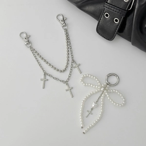 Detail showing multi-layer silver chain with cross charms and pearl bow bag accessory