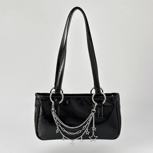 Detail of glossy black shoulder bag with silver star charms and layered metal chains