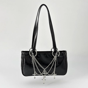 Detail of silver multi-layer chains and cross charm on a black patent leather handbag