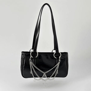 Detail of silver multi-layer chains with star charms on a black patent shoulder bag