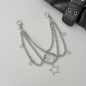 Detail of layered silver metal bag chain with star charms and lobster clasps on leather bag