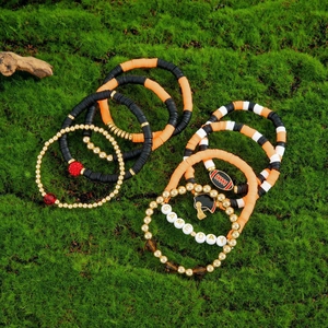 Detail of colorful Game Day bracelet set with football charms and beads on green moss