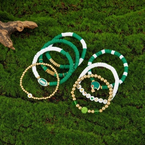 Detail of 7-piece rugby game day bracelets with green heishi beads and football charms