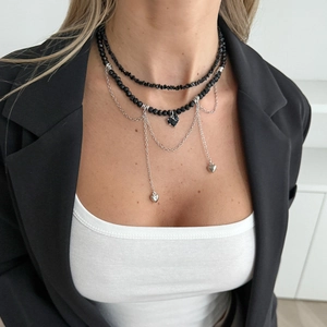 Détail d'un collier multicouche de perles noires avec pendentifs cœur sur un mannequin