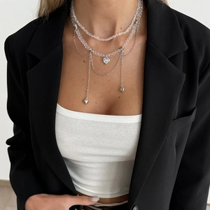 Détail d'un collier multicouche avec perles transparentes et breloques en cœur