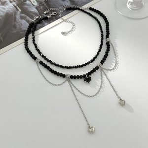 Détail du collier à plusieurs rangs avec perles noires et pendentifs en cœur