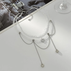 Vue détaillée du collier multicouche argenté avec pendentifs cœur et étoile et perles