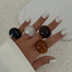Set aus vier bunten breiten Harzringen in Schwarz, Weiß, Amber und Rot auf der Hand