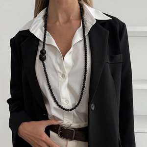 Long black beaded necklace with asymmetric large bead accents on elegant business suit