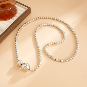 Detailed view of layered silver beaded necklace with large polished metal spheres