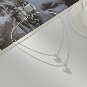 Detailed view of a silver double-layered necklace with two round pearl pendants