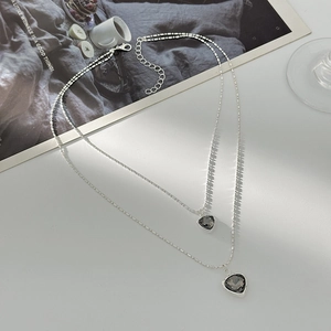 Double-layered beaded necklace featuring two heart-shaped dark grey gemstone pendants